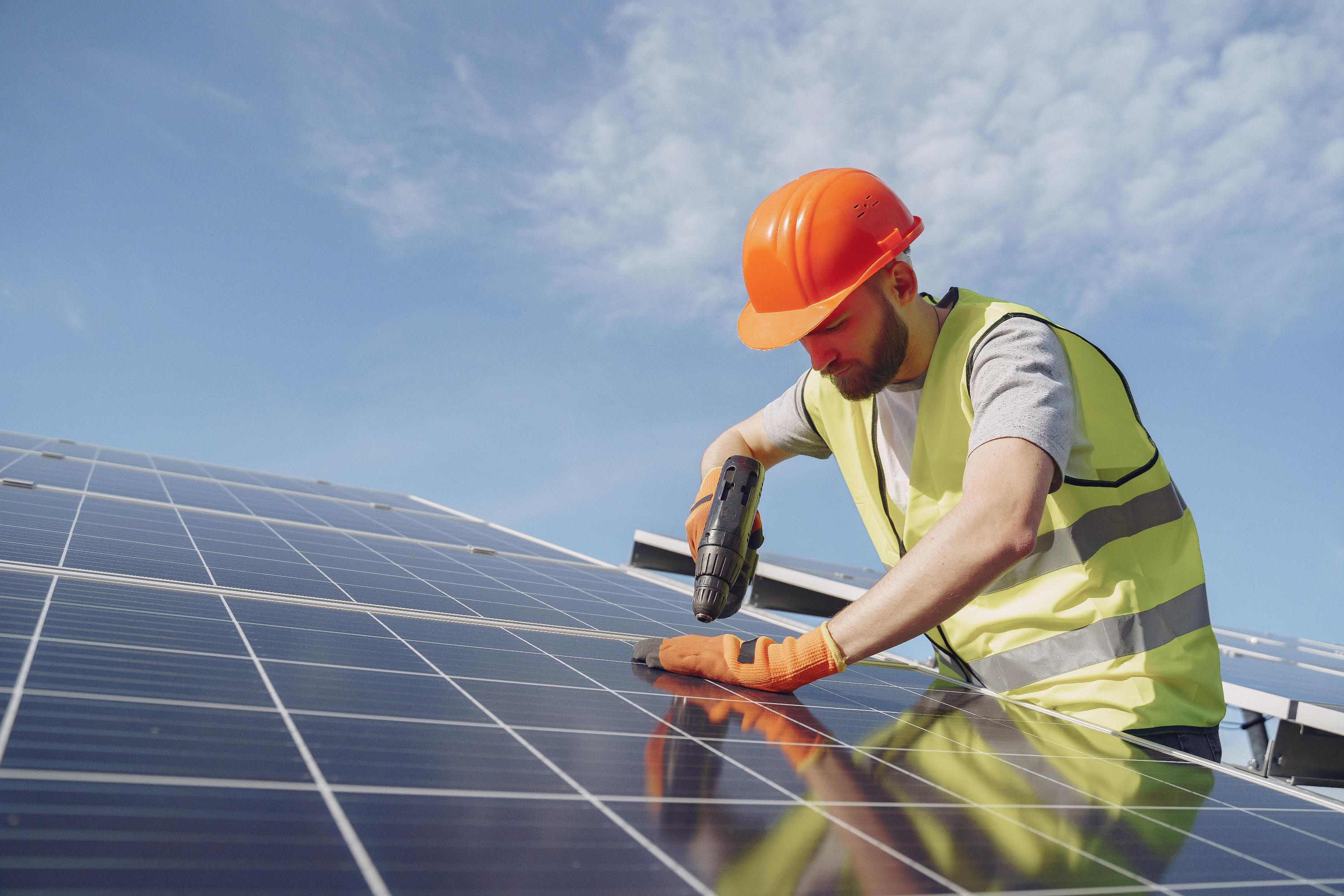 Worker on roof installing solar panels